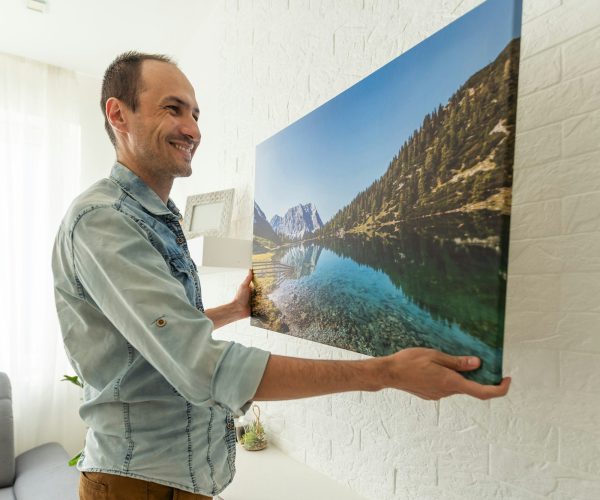 man holds canvas in the interior